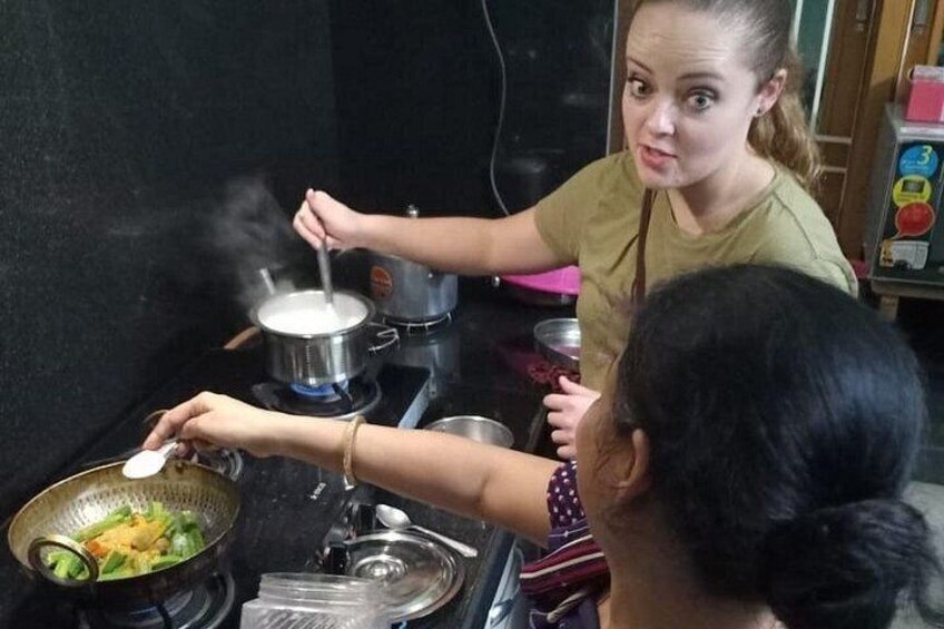 Twee personen koken in een keuken, met pannen op het fornuis. 2