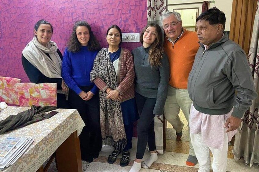 A group of people standing indoors, a table with papers, and a patterned wall. 5