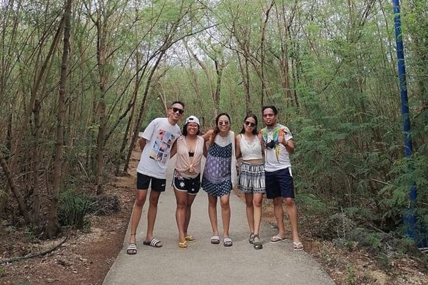 A group of people standing on a paved path in a forested area. 2