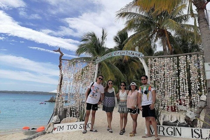 A group of people standing in front of a decorative arch with a sign that reads 'Welcome to Virgin Island.' 5