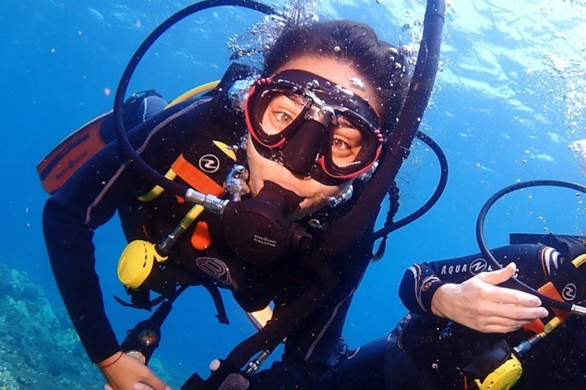 Une personne pratiquant la plongée sous-marine, vêtue d'une combinaison de plongée noire et portant un masque de plongée. 1