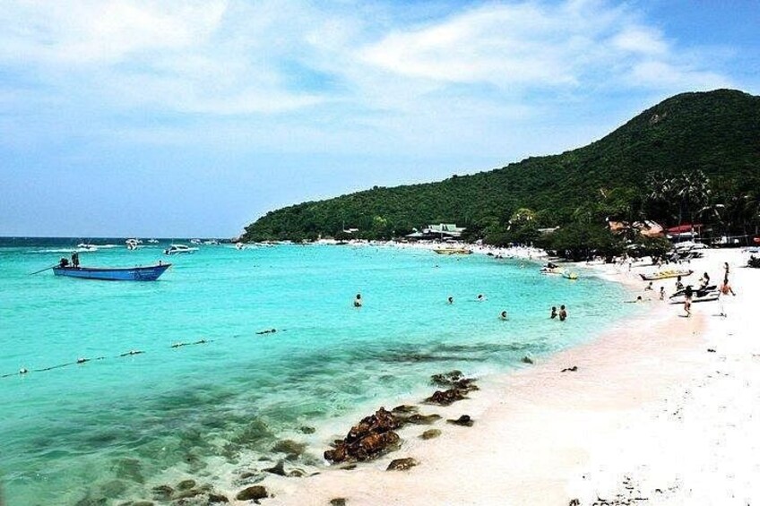 A beach with clear turquoise water, a boat, and a mountainous backdrop. 3