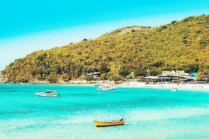A coastal landscape with clear turquoise waters, boats, and a hill with dense vegetation. 4