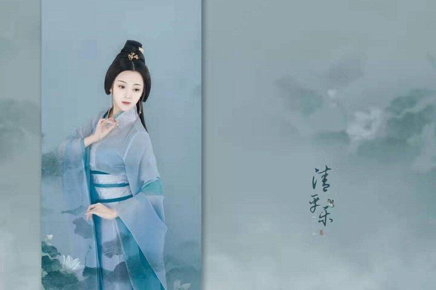 A person in traditional attire with a blue robe and a white headpiece, standing against a backdrop with a cloudy sky. 5