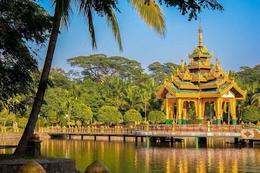 A golden pagoda with a reflection in the water, surrounded by palm trees and greenery. 2
