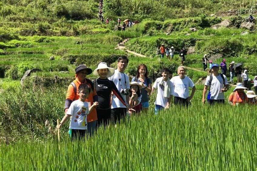 A group of people standing in a field with tall grass and a hilly landscape in the background. 5