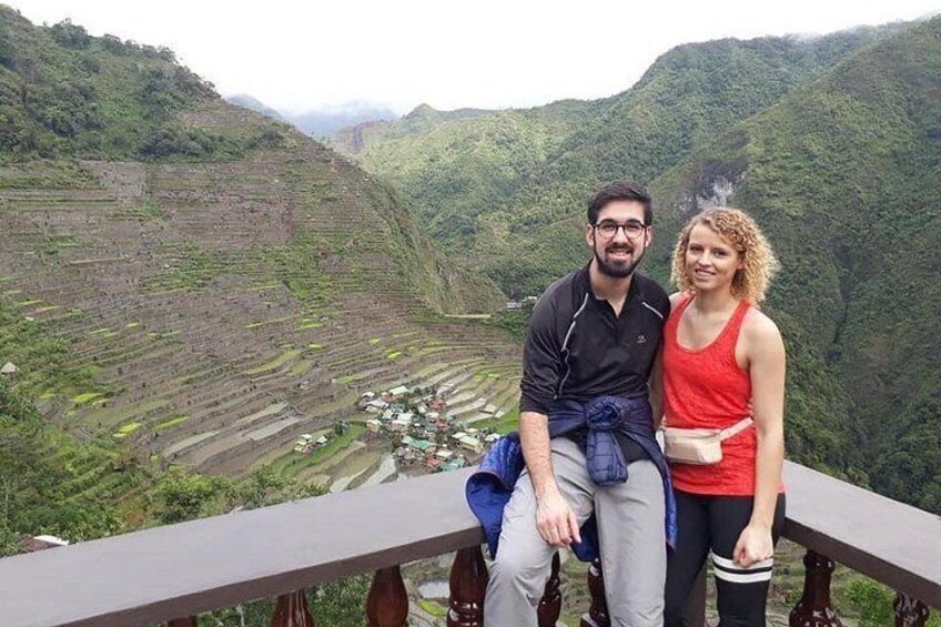 A couple sitting on a bench overlooking terraced fields in a hilly landscape. 4