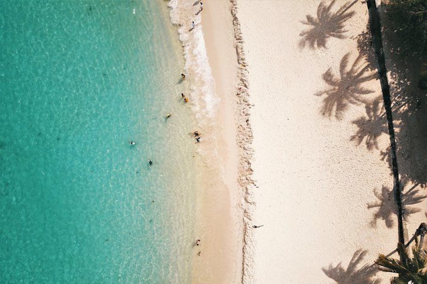 A beach with clear turquoise water, white sand, and palm tree shadows. 4