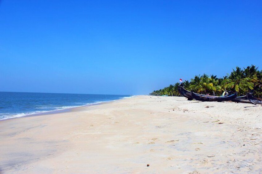 A beach with a clear blue sky, calm sea, and a row of boats on the shore. 5
