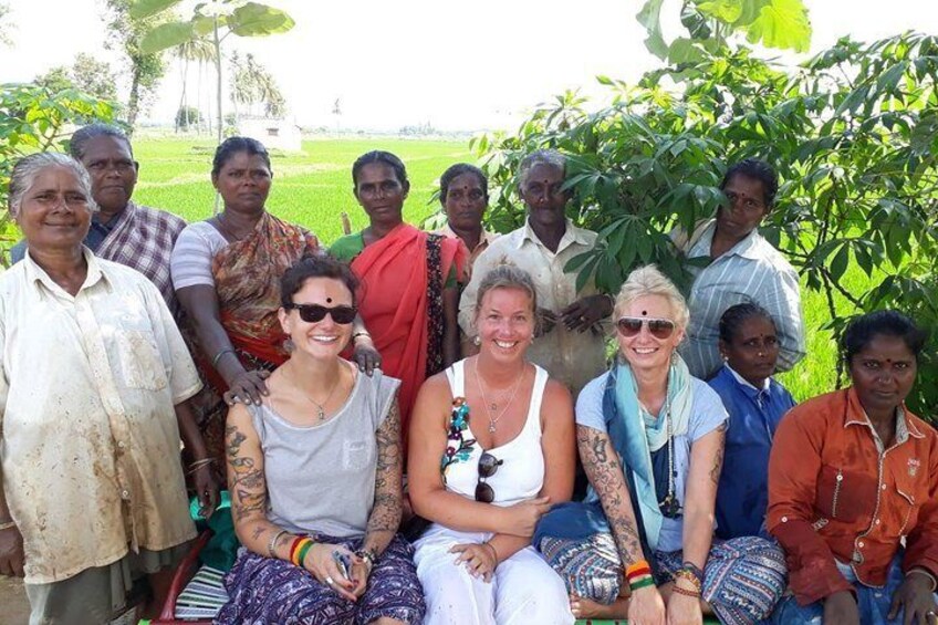 A group of people in a rural setting with green fields and trees in the background. 2