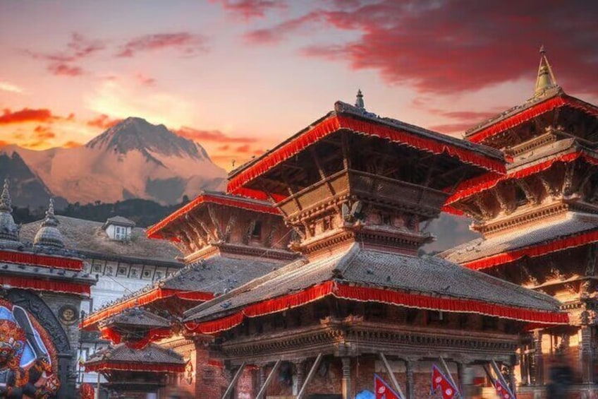 A traditional multi-tiered building with red roofs, set against a backdrop of a mountain and a sunset sky. 5