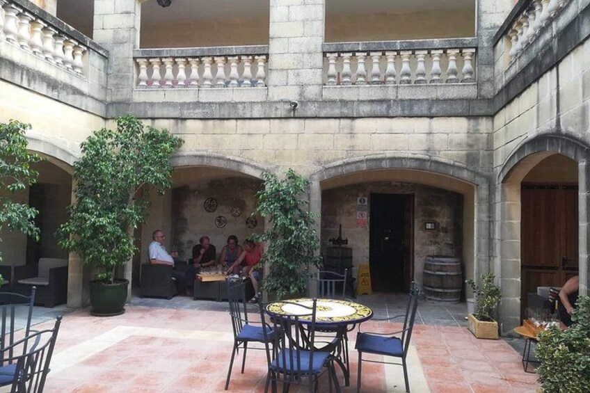 Un patio con arcos de piedra, una mesa redonda y sillas. 3