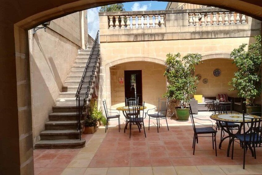 Un patio con asientos al aire libre, una escalera y la fachada de un edificio. 1