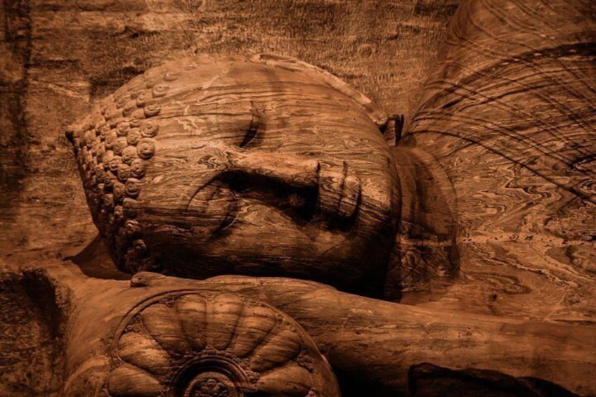 Un'imponente scultura in pietra, finemente intagliata, raffigura una figura sdraiata con una complessa cuffia e decorazioni elaborate sul corpo. 2