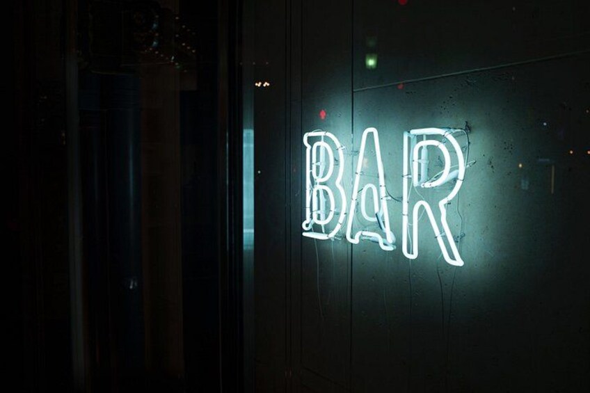 A neon sign spelling 'BAR' on a dark wall. 4