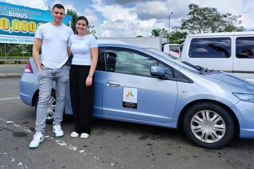 A blue car with a sticker on the side, a parking lot, and a billboard in the background. 2