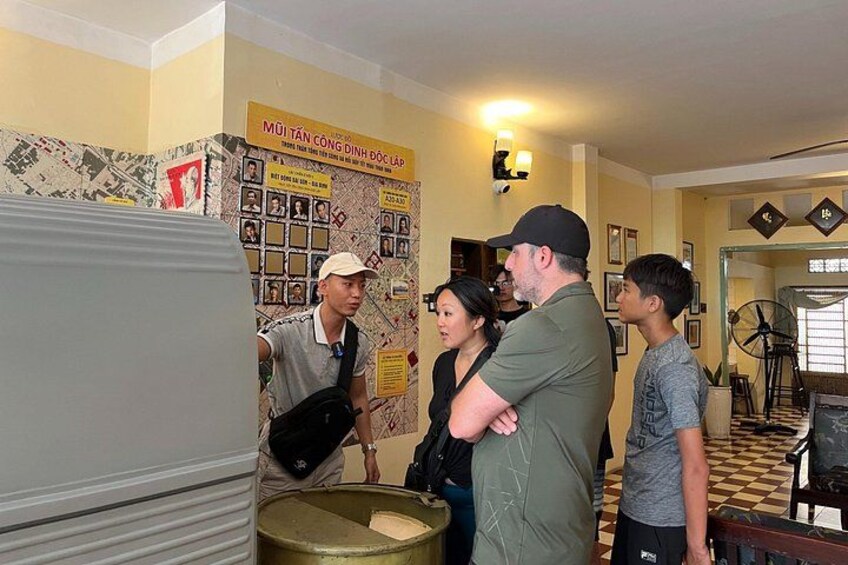 Een groep mensen in een ruimte met een muur vol foto's en een bord. 5