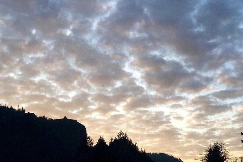 A sunset sky with clouds over a forested landscape. 4
