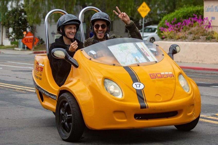 Un'auto gialla con il numero 17, un autista e un passeggero che indossano caschi. 2