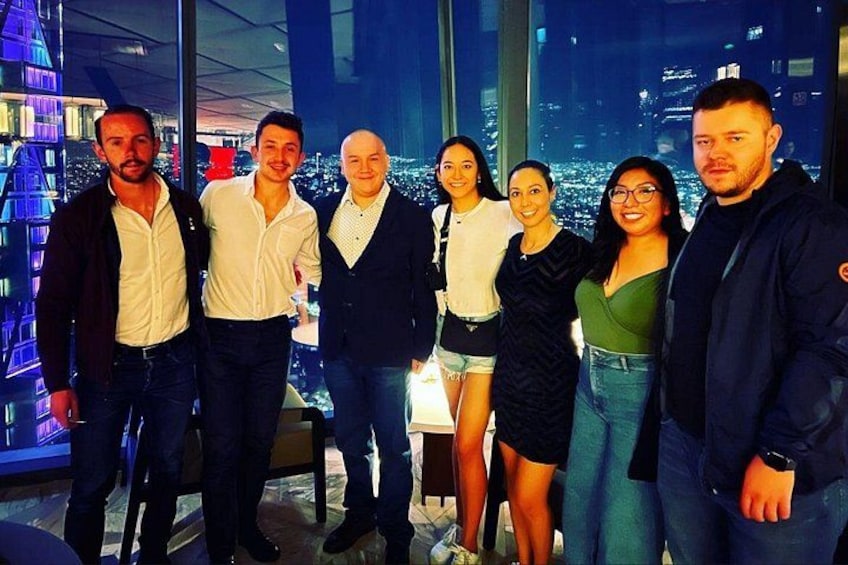 A group of people standing indoors with a cityscape in the background. 5