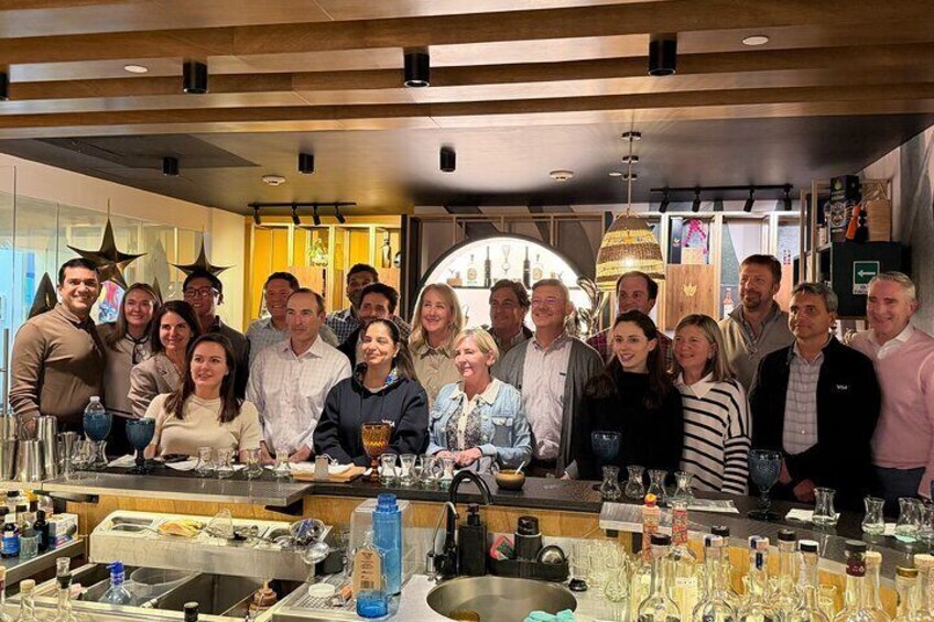 A group of people gathered around a bar area with glasses and bottles. 5