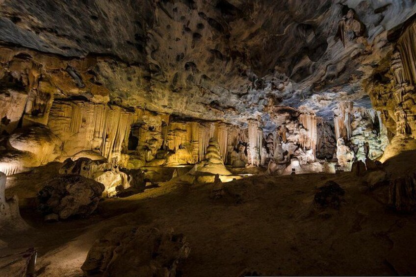 Una cueva con estalactitas y estalagmitas, iluminada por luces artificiales. 2