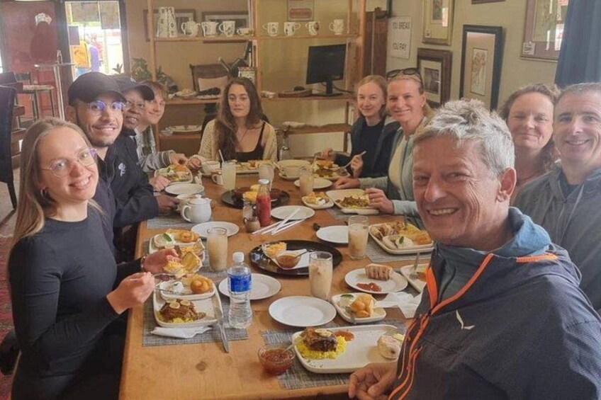 A group of people sitting around a table with various dishes and drinks. 1