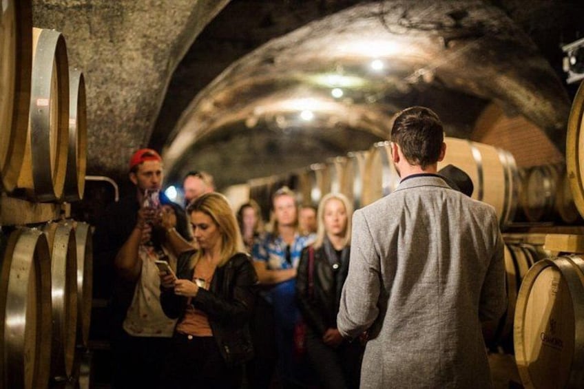 A group of people in a wine cellar with barrels. 3