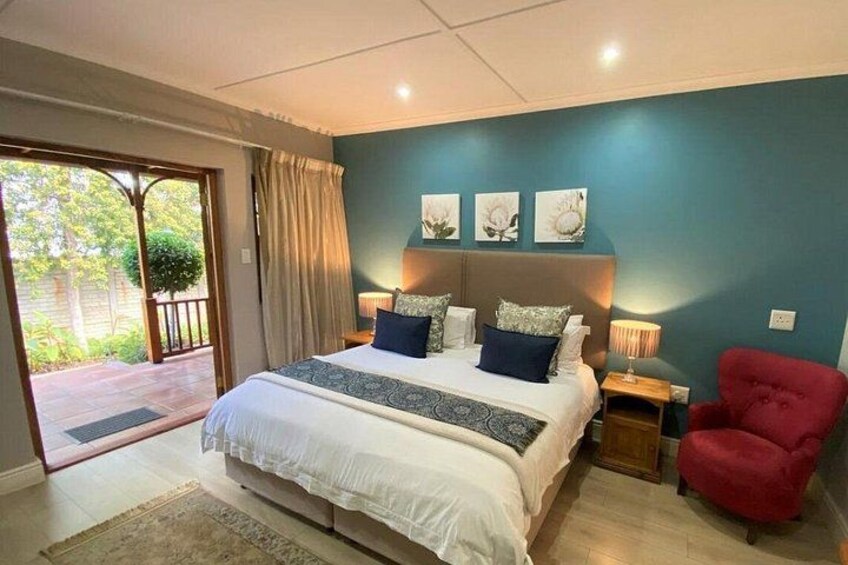 A bedroom with a bed, a red chair, and a view of the outdoors. 2