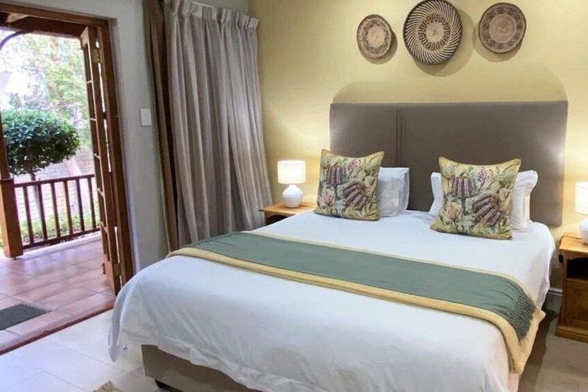 A neatly made bed with floral pillows, a wooden headboard, and a view of a balcony. 5