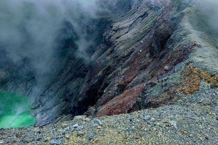 A volcanic landscape with a steep, rocky slope and a greenish glow at the base. 3