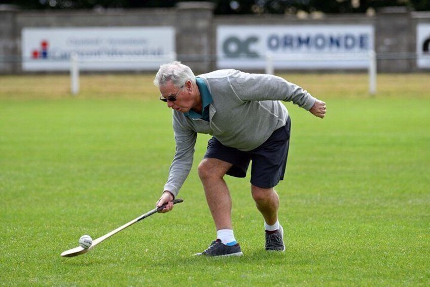 A person playing golf on a green field with a golf club and ball. 2