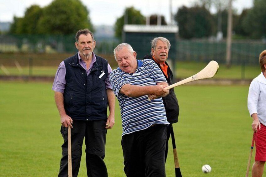 A group of people playing a ball game with bats on a grassy field. 5