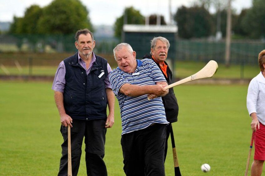 Three people playing a ball game with bats on a grassy field. 2