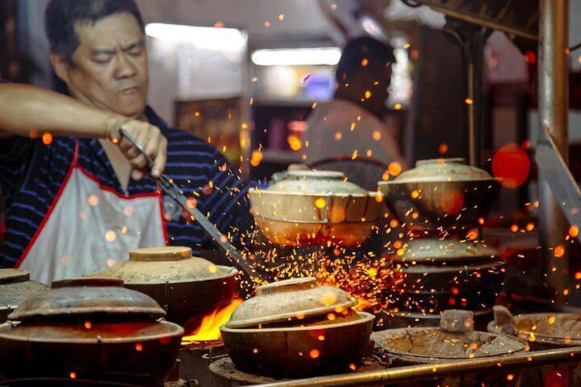 A person working with a blowtorch, cooking food in large pots. 1