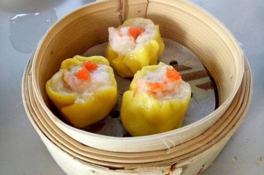 A bamboo steamer with three dumplings, one of which is cut open to reveal a filling of shrimp and roe. 4