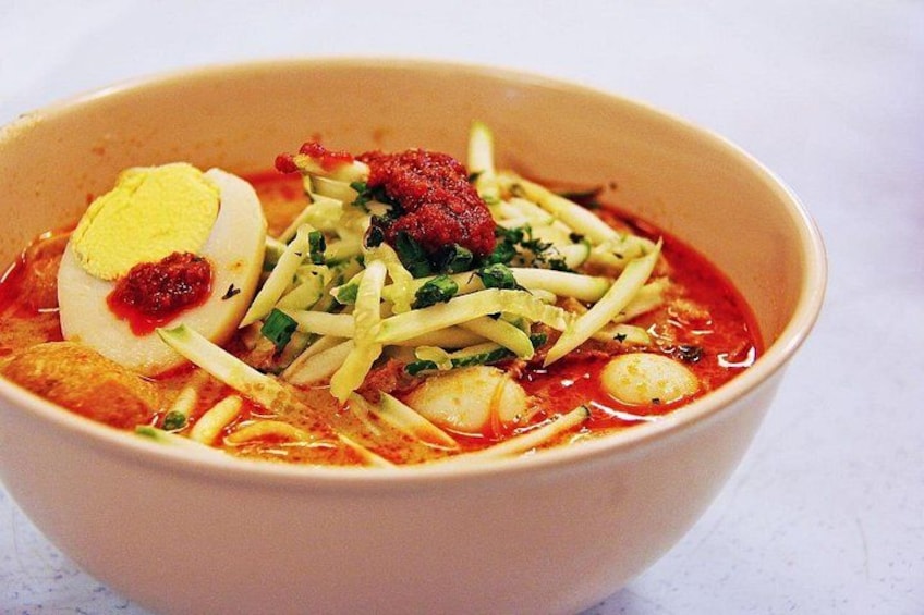 A bowl of soup with noodles, a boiled egg, and various toppings. 2
