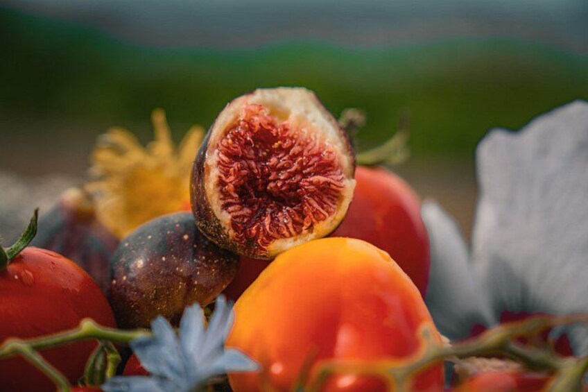 Verschillende soorten fruit, waaronder tomaten, vijgen en mogelijk een perzik, met de nadruk op de doormidden gesneden vijg die zijn binnenkant toont. 2
