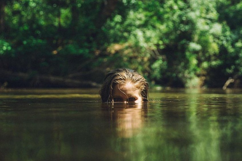 Una persona nuota in un corpo d'acqua circondata da vegetazione lussureggiante. 4