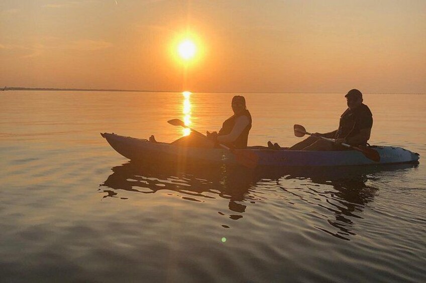 Two people kayaking on a calm body of water during sunset. 3