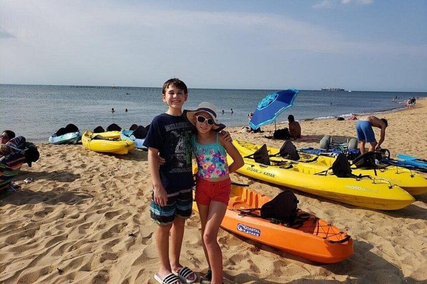 A beach with kayaks and a person standing in the foreground. 2