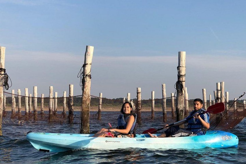 Two people kayaking on a calm body of water with a wooden dock in the background. 2