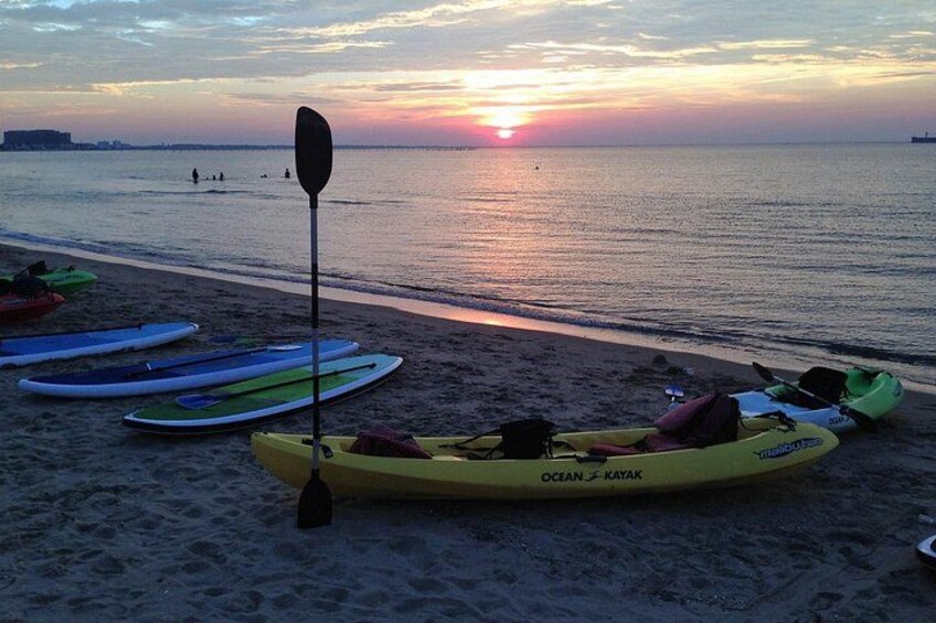 Kayaks on a beach with a sunset in the background. 1