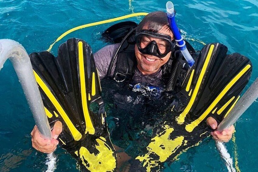 Una persona in piscina con pinne gialle e nere, che tiene uno snorkel e una maschera. 2
