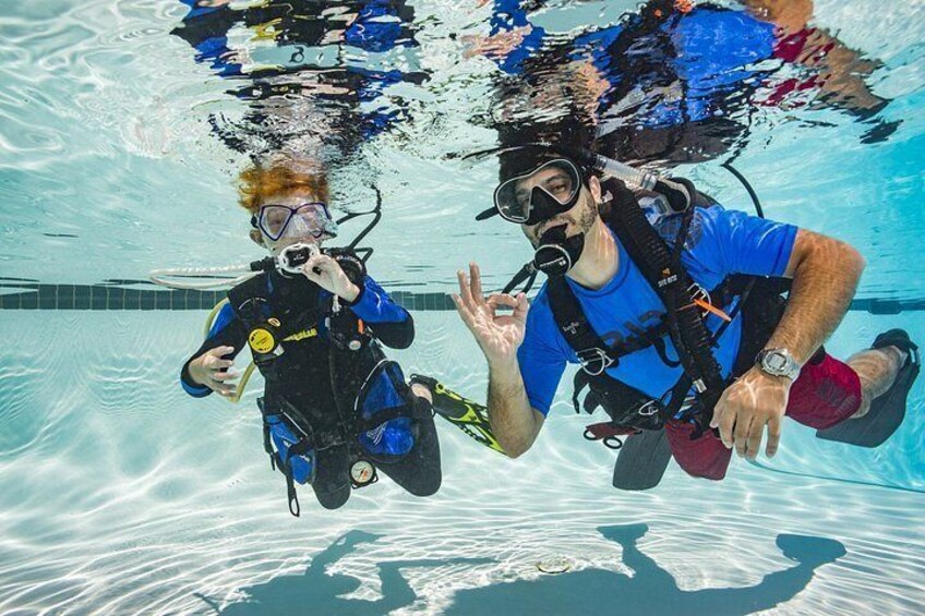 Zwei Personen tauchen unter Wasser in einem Pool. 2