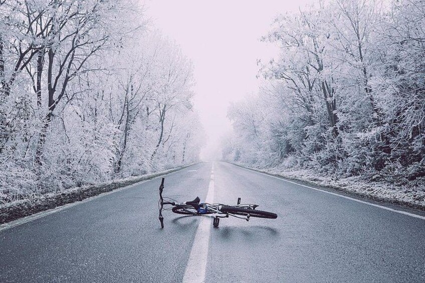 A snow-covered road with a bicycle and a person standing on the side. 4