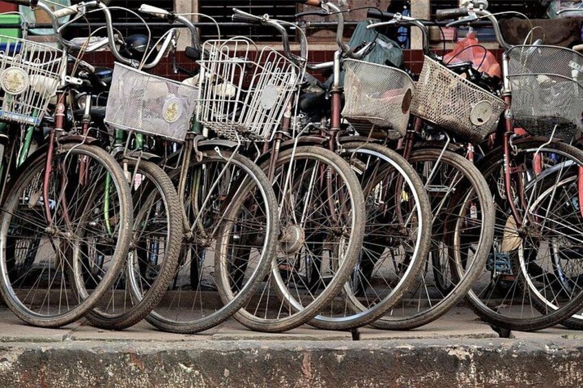 A row of bicycles with baskets, parked on a sidewalk. 2