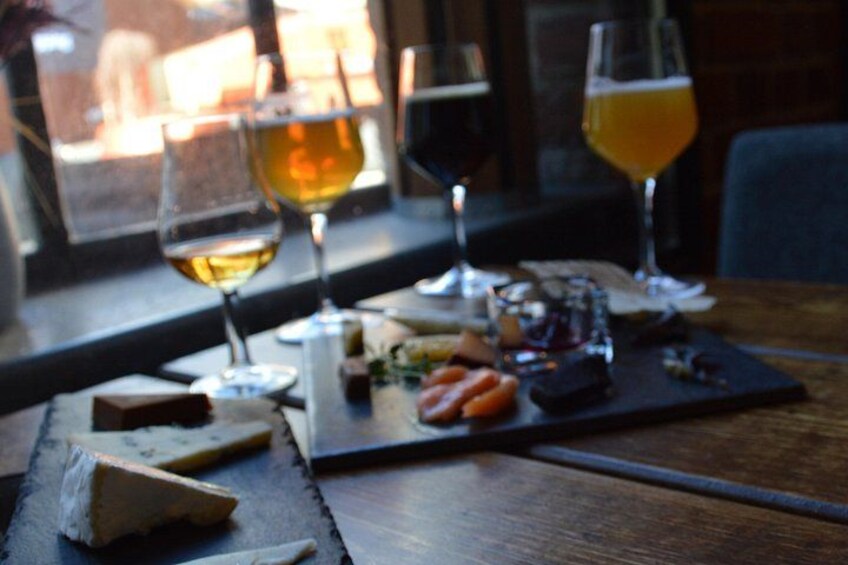 Ein Holztisch mit einer Käseplatte, Weingläsern und einem Bierglas. 3