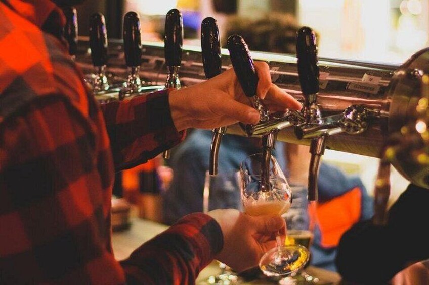 A person pouring beer from a tap into a glass. 5