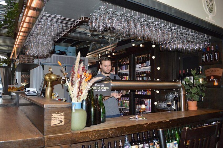 A bar with a bartender, shelves of bottles, and hanging glasses. 2